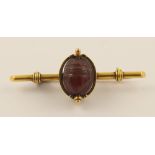 A yellow metal bar brooch set with an of the antique scarab carved bead with an intaglio verso