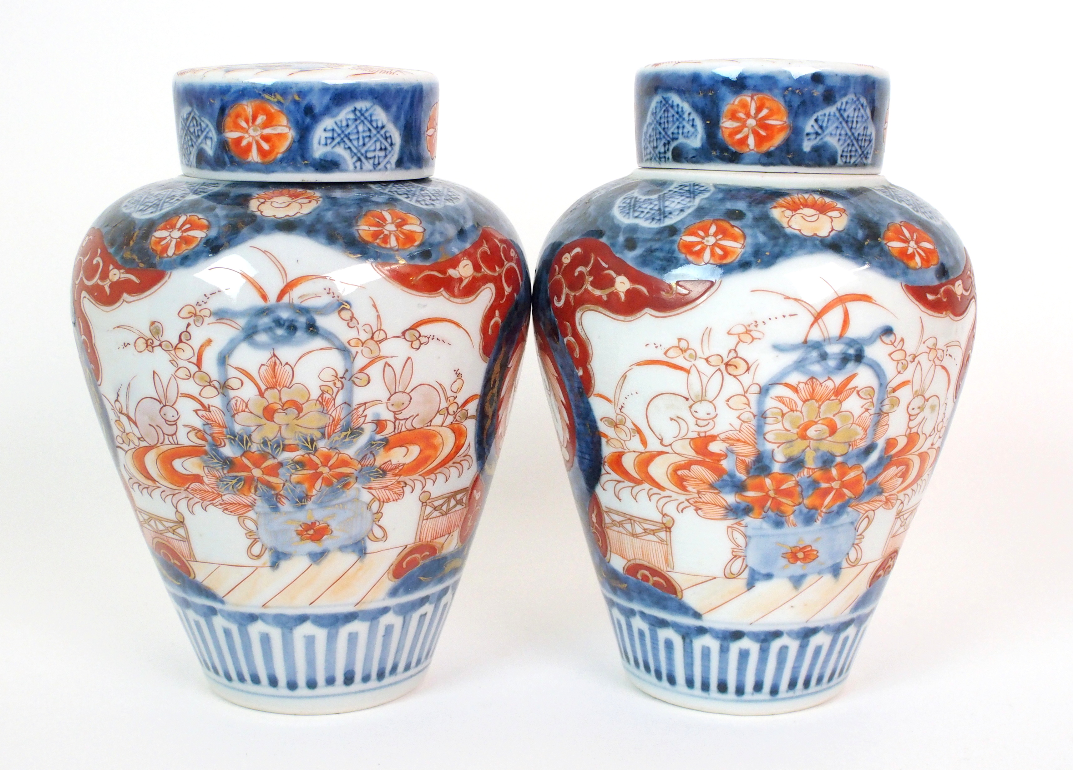 A pair of Imari baluster vases, covers and liners  painted with jardinieres of flowers and rabbits