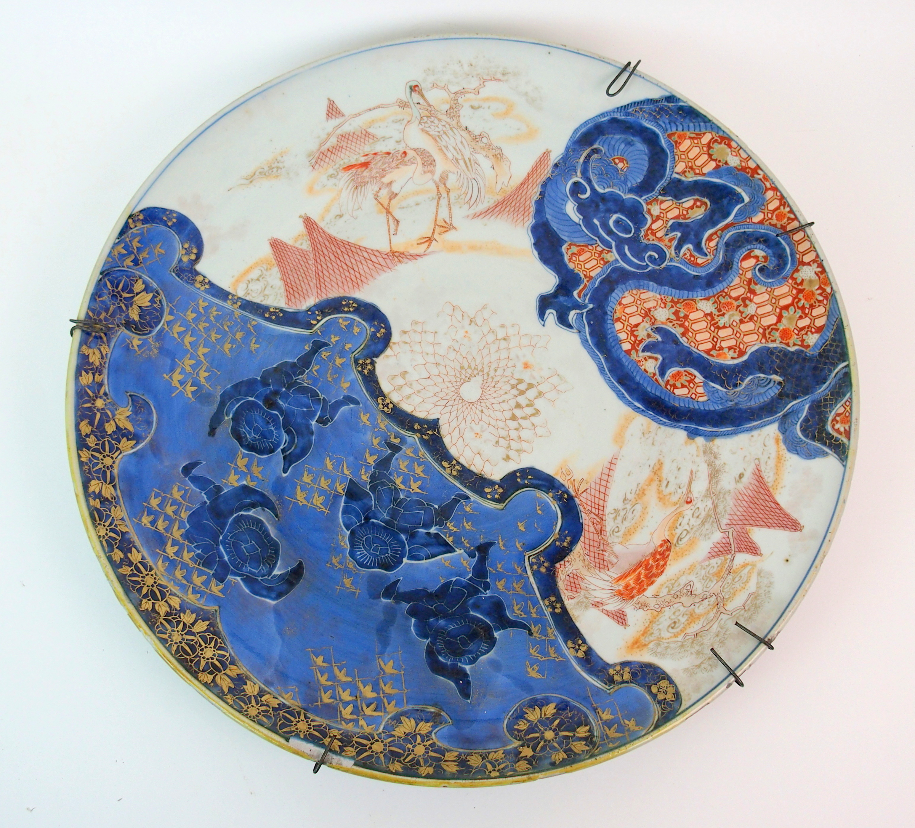 An Imari dish painted with fishermen, herons and a dragon (rim chips), signed, 50cm diameter