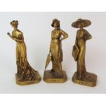 Three French gilt bronze figureseach depicting a standing lady in early 20th Century attire and