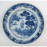 A Chinese blue and white charger painted with a man standing on an island beneath a pine tree