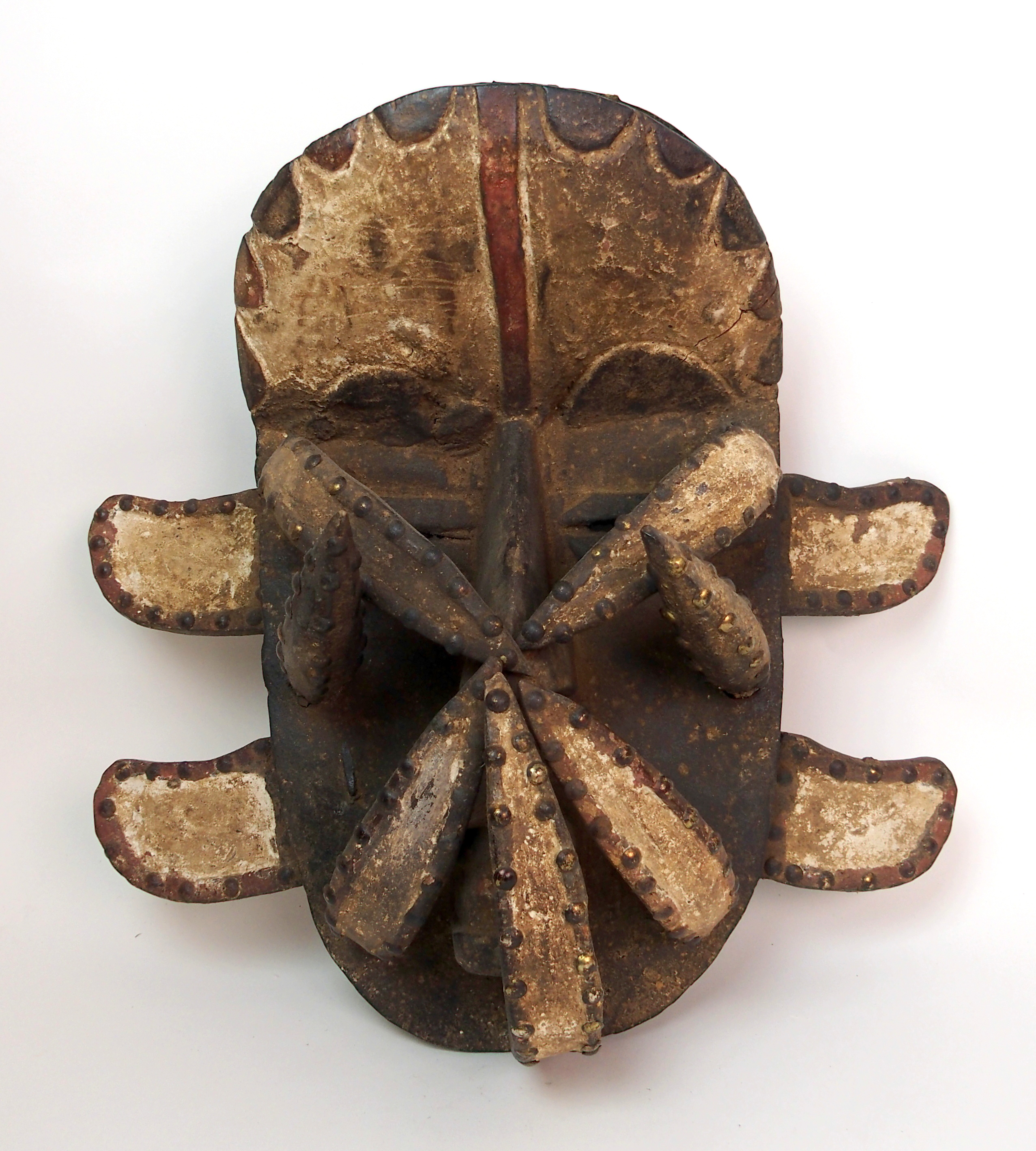 An African carved and painted wood mask with brass studded decoration, 40cm high