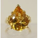 A 10ct gold ring set with a pear shaped citrine set in a six claw basket mount with chevron designed