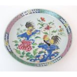 A Chinese famille rose dish painted with two cockerels amongst peonies issuing from rockwork