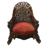 An Anglo Indian carved, pierced and gilt armchair with berried foliage and scrolls joined by