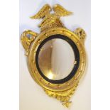 A 19th Century giltwood and gesso convex circular wall mirror with eagle surmount holding two