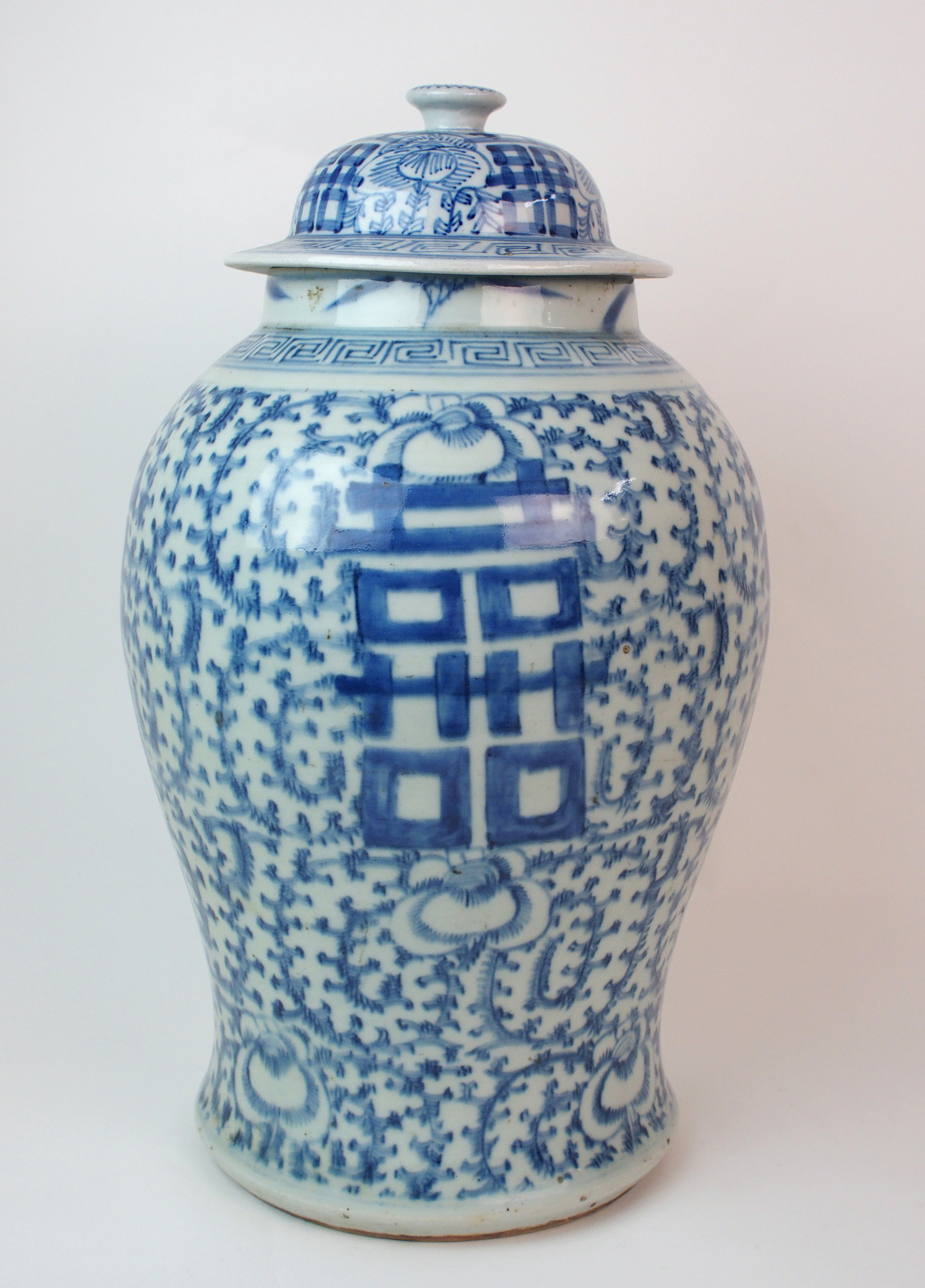 A Chinese blue and white tea jar painted with calligraphy and scrolling foliage, the domed cover and