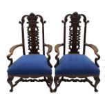 A pair of stained parlour chairs carved with a male and female head above a pierced scroll splat,