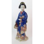 An Arita figure of a lady standing holding a fan and wearing a floral kimono, 32cm high