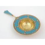 A Scandinavian silver gilt and enamel tea strainer marked 925, the circular pierced bowl with blue