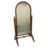 A Victorian walnut cheval mirror the arched frame on fluted supports and scroll legs with brass