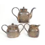 A Chinese silver three piece tea service cast with ogival panels of bamboo comprising; teapot, two