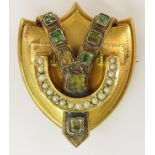 A Victorian shield shaped brooch set with split pearls and foil backed gemstones mounted in yellow