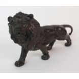 A Japanese bronze model of a prowling lion with head raised, signed, 26cm long