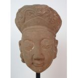 A Sung sandstone carved head of a noble woman with headdress decorated with foliate scrolls, her