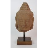 A Khmer sandstone head of Buddha with serene smile with large cranial bump representing wisdom,