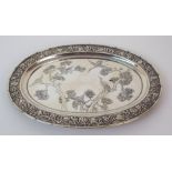 A Chinese silver oval card tray chased with herons amongst pine trees within a chrysanthemum