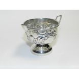 A Victorian silver cream jug hallmarked Birmingham 1900 with embossed decoration and raised on