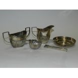 A two handled silver sugar bowl of half reeded form, together with a matched silver cream jug, a