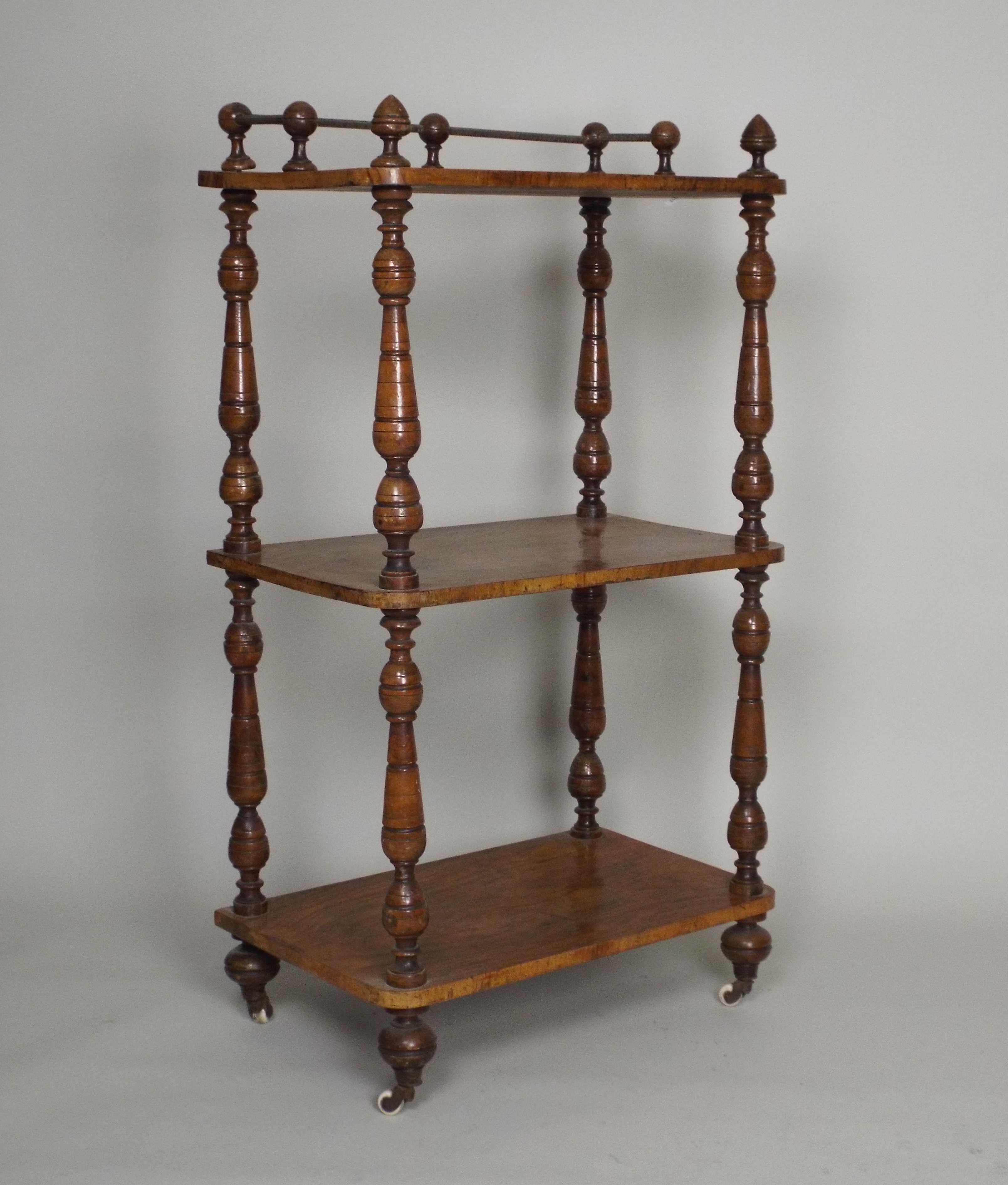 A late Victorian walnut three tier what-not, of rectangular form, with slender turned corner