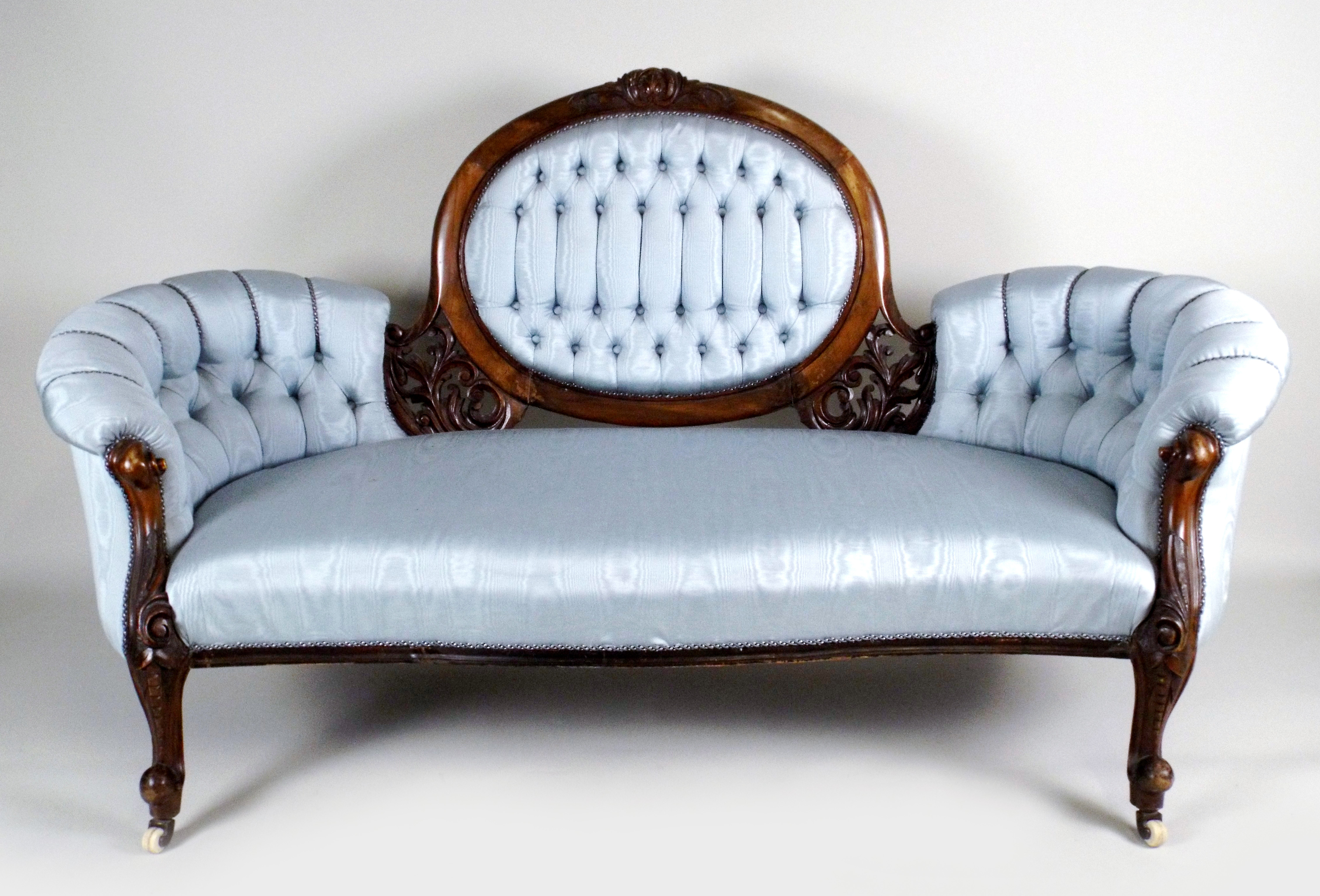 An early Victorian walnut sofa, the central oval padded back with leaf carved show frame, flanked