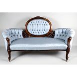 An early Victorian walnut sofa, the central oval padded back with leaf carved show frame, flanked