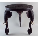 A late 19th century hardwood Indian elephant trunk table with carved circular top on three elephant