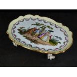 A Meissen porcelain tray on four paw feet, outside decorated with a scene of figures in a garden