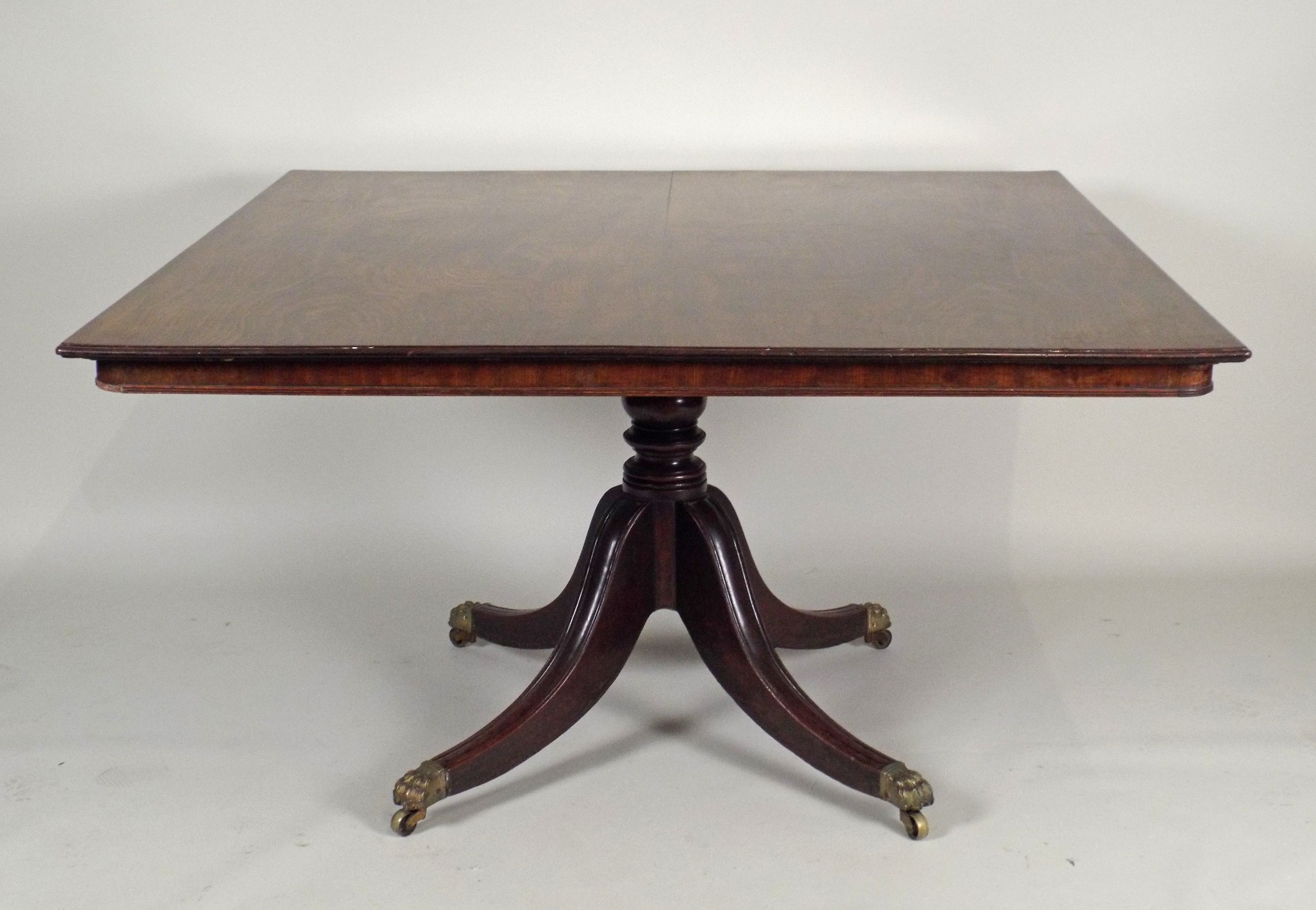 A George IV mahogany triple pillar dining table the rectangular top with moulded edge and drop-leaf