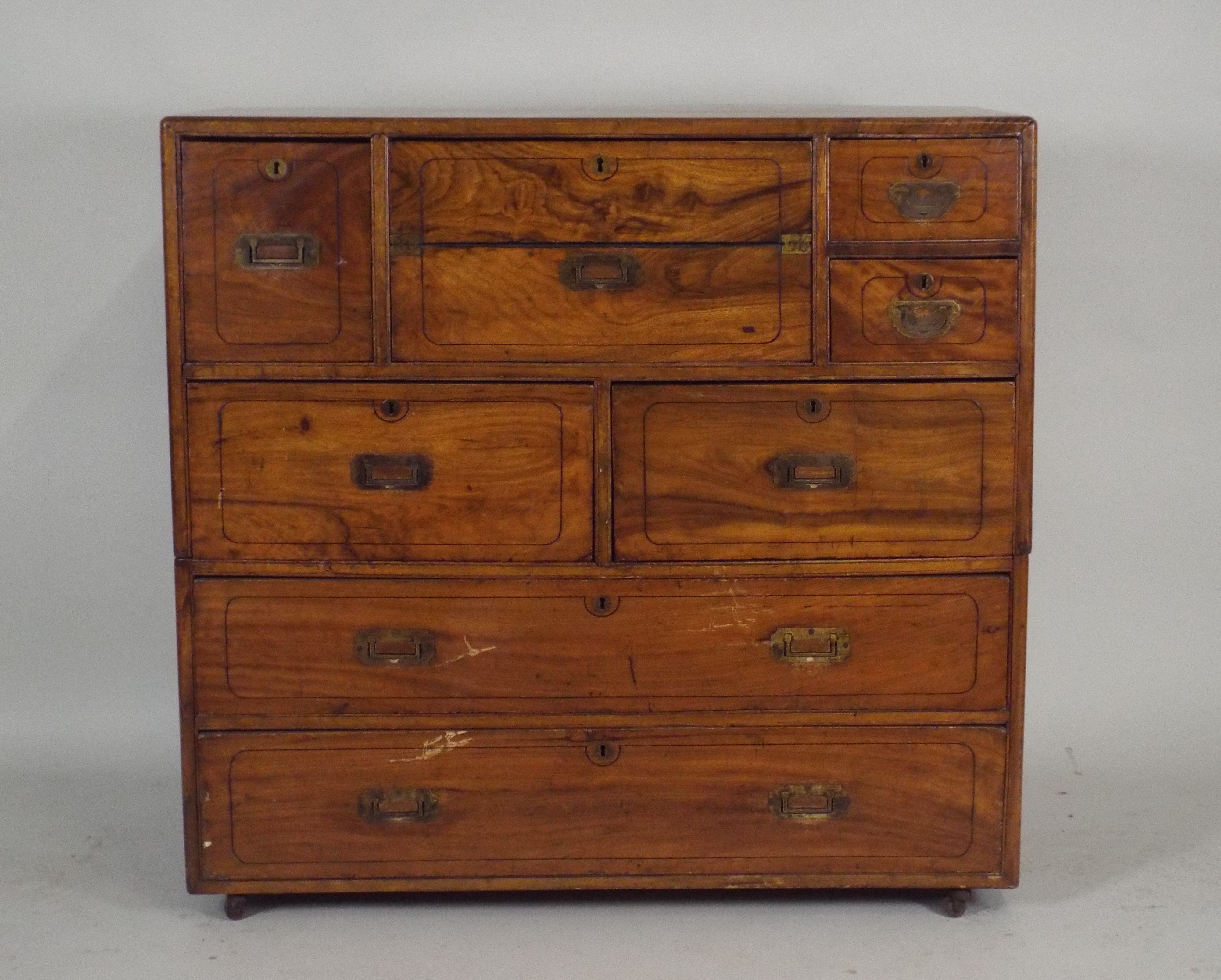 A 19th century teak campaign style desk/chest, the rectangular top with rounded edges over a central