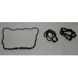 A carved Jet bead necklace together with two further necklaces