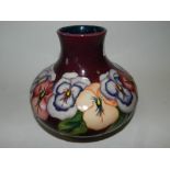 A modern Moorcroft vase tubelined with pansies against a claret ground