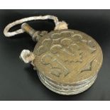 A Moroccan brass powder flask, late 19th/ early 20th century, of circular form with flat sides,