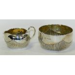 A silver half reeded sugar bowl together with a matched half reeded silver cream jug.