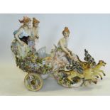 A Sitzendorf figural group of three ladies riding a chariot, pulled by two winged beasts (a.