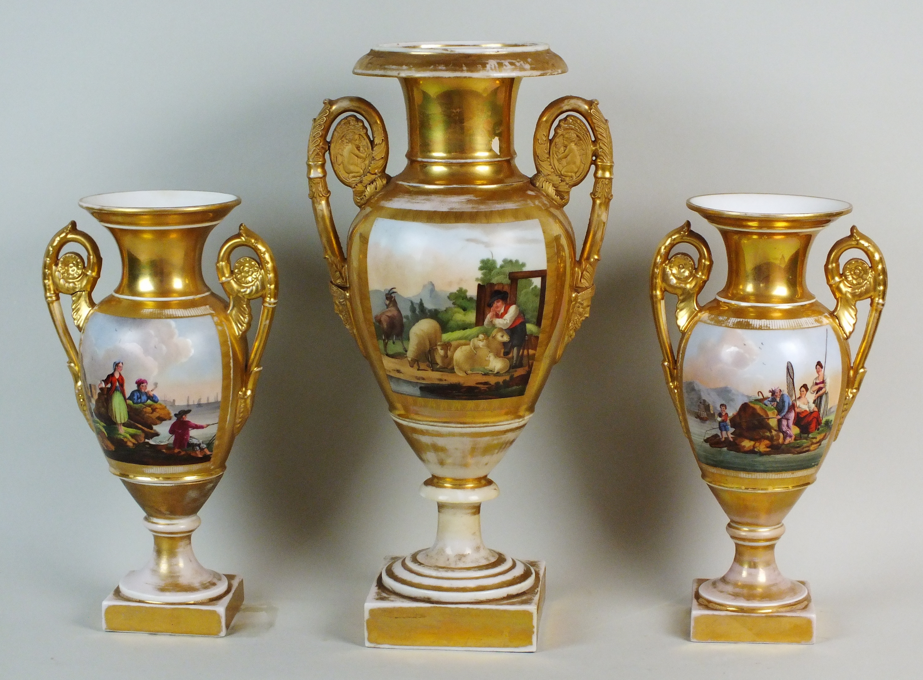 A matched garniture of three Paris Empire style porcelain gilt ground twin handled vases,