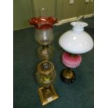 Three late Victorian oil lamps, the first with a brass reeded column,