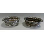 A pair of silver plated wine coasters with scroll and foliate cast rims