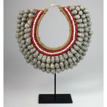 A woven seed & shell necklace on stand from Papua New Guinea,