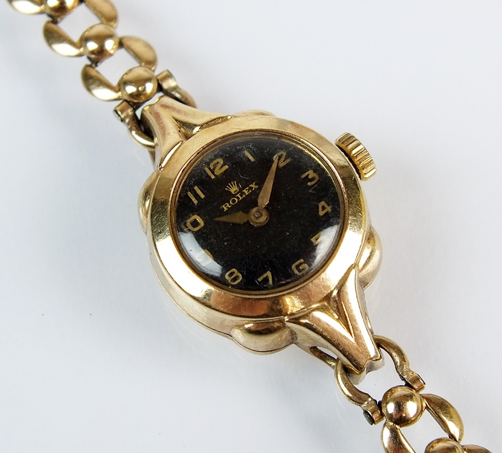 A lady's 9ct gold Rolex wristwatch, the circular black dial with gold Arabic numerals, manual wind,