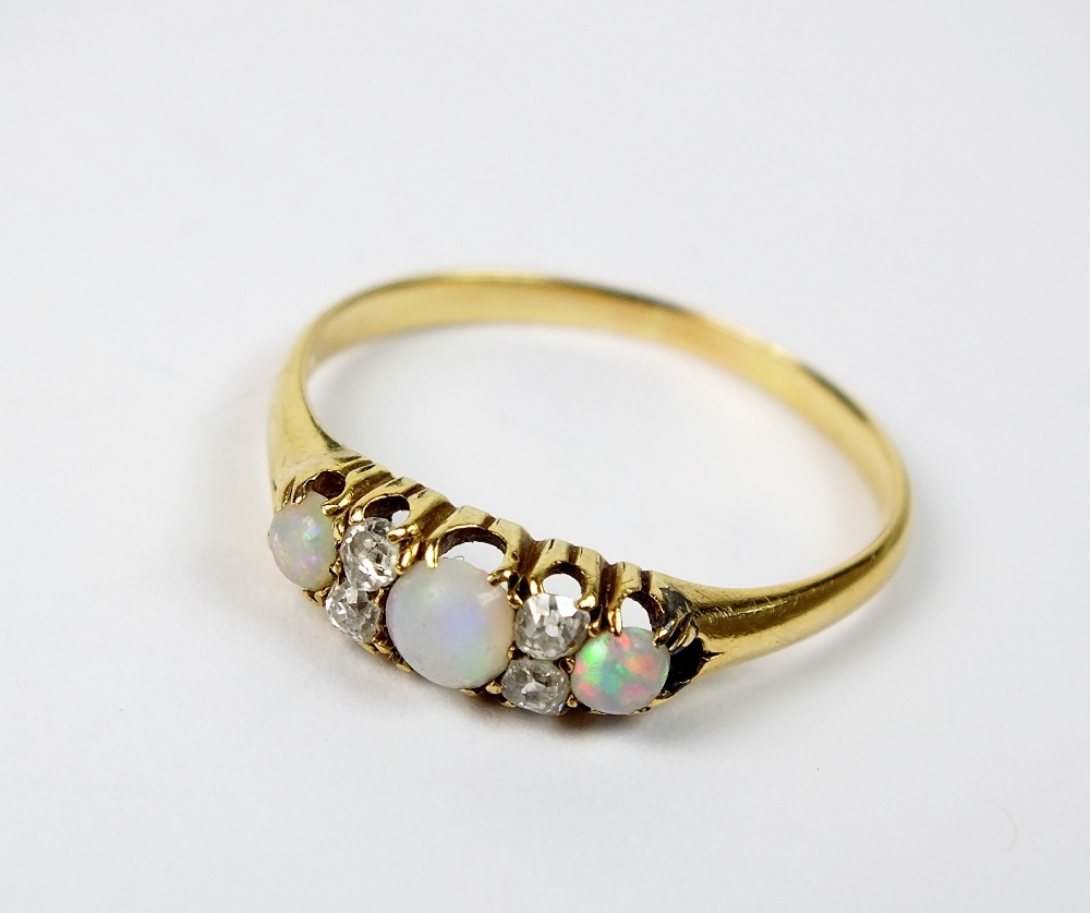 An early 20th century opal and diamond ring, designed as three graduated circular cabochon opals,