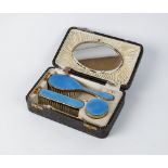 A cased gold plated and guilloche enamel dressing table set, comprising; hair brush, clothes brush,