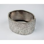 A Victorian silver hinged bangle, with engraved foliate scrolling decoration,