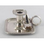 A small silver rectangular chamber candlestick with gadrooned rim and reeded loop handle by Nathan