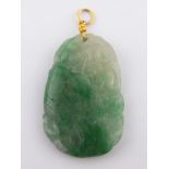 A carved jade pendant with yellow metal