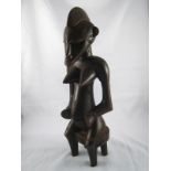 An Ivory Coast Senufo tribal figure of a woman seated on a stool. ht.42cm.