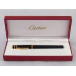 A Cartier "Three Golds" gold plated ballpoint pen in presentation box with booklets.