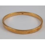 A yellow metal bangle, marked 18ct, internal width approx 6.5cm, 12.8 gms.