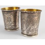 A pair of Russian silver vodka tots, the bases with incised eagles, the sides floral engraved.