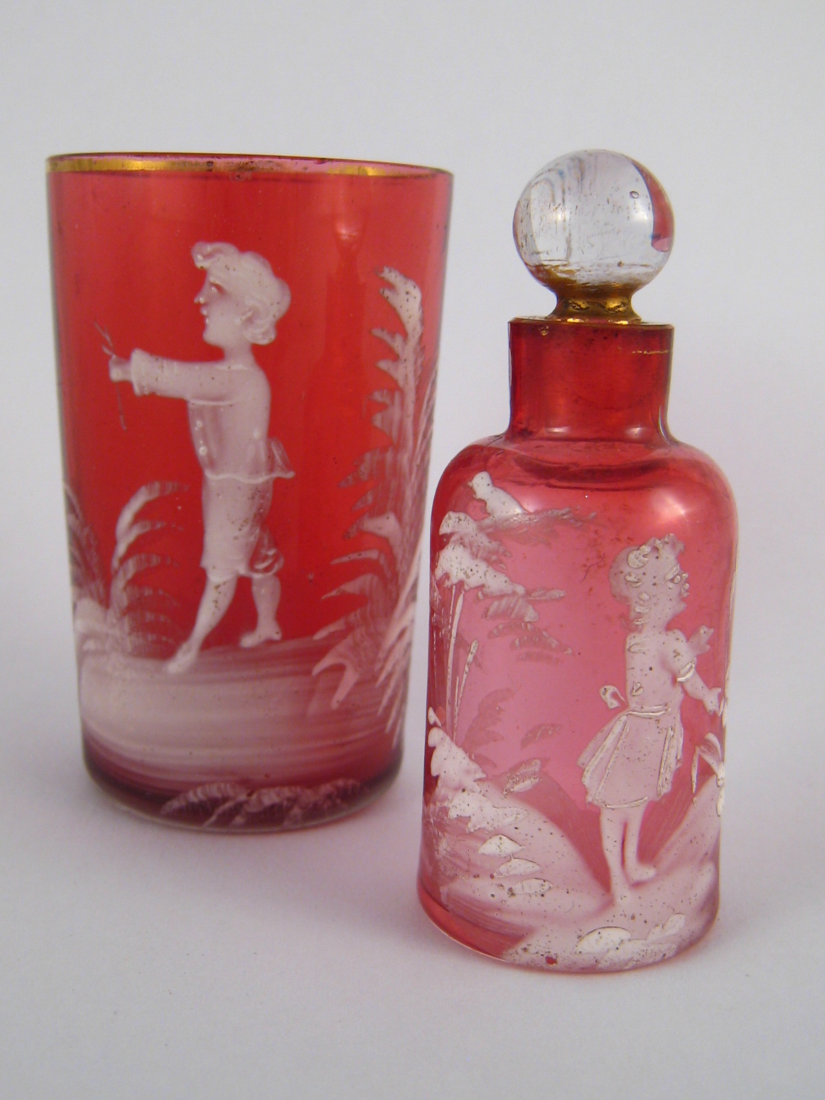 Two pieces of cranberry glass with "Mary Gregory" white enamel scenes,